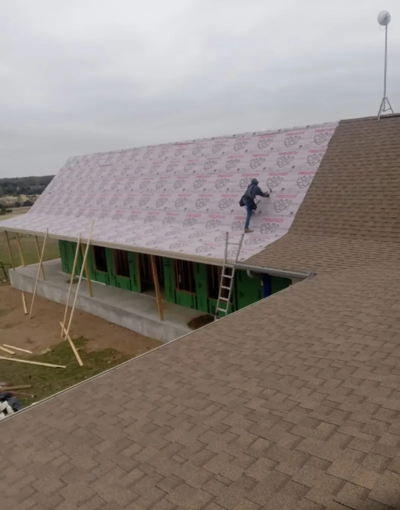 Worker preparing underlayment for a metal roof installation in Bartlett